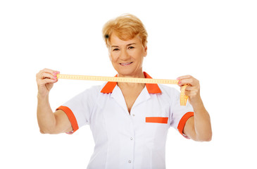 Smile elderly doctor or nurse holds measuring tape