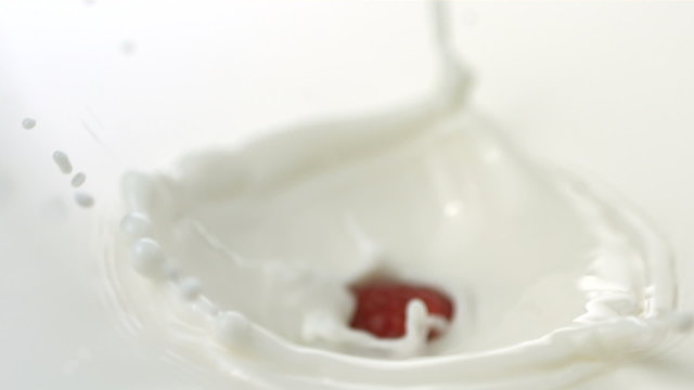 Raspberry splashing into cream, slow motion