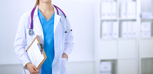 Woman doctor standing with folder at hospital