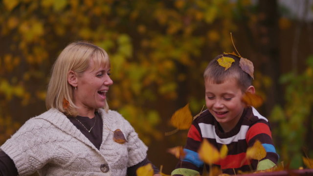 Mother and son throwing fall leaves, slow motion