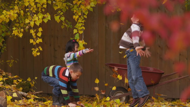 Three children throwing fall leaves, slow motion