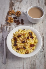 Cooked millet groats on white plate and cup of coffee with milk, healthy food and nutrition