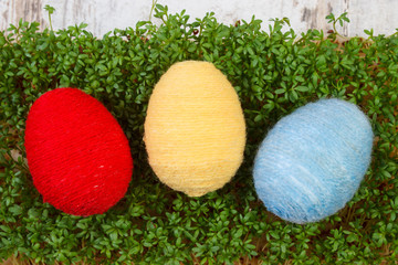 Easter eggs wrapped woolen string and green cress, decoration for Easter