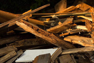 Holzbretter ungeordnet auf einem Haufen in verschiedenen Holztönen in der Abendsonne