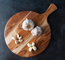 Whole garlic and cloves on wooden chopping board and grungy textured background. Top view.