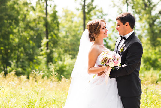 Groom and Bride in a park. Bridal wedding bouquet of flowers