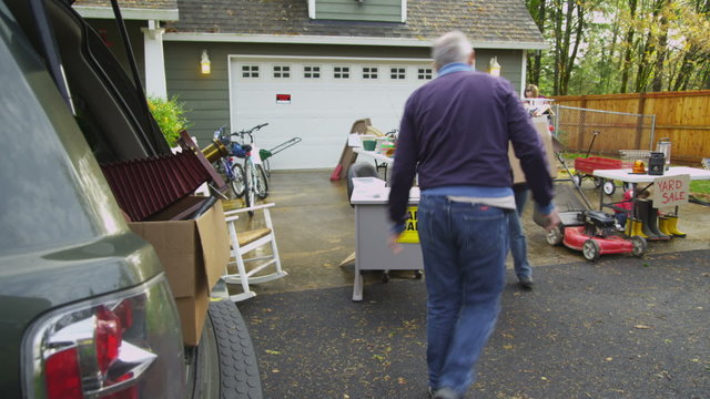Mature couple load up car with garage sale items