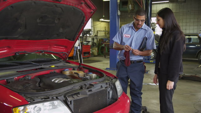 Mechanic in auto shop helps customer with digital tablet