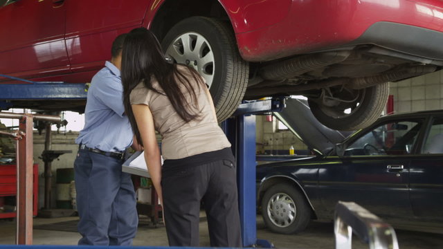 Mechanic in auto repair shop helps customer