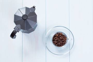 Coffee cup and moka pot with coffee beans on table