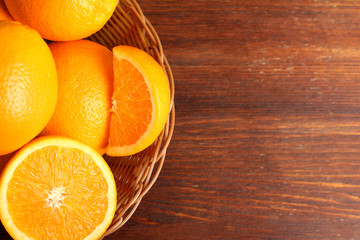 delicious sliced oranges are in the basket on brown wooden table