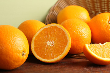 delicious sliced oranges fell out of the basket on brown wooden table on light background