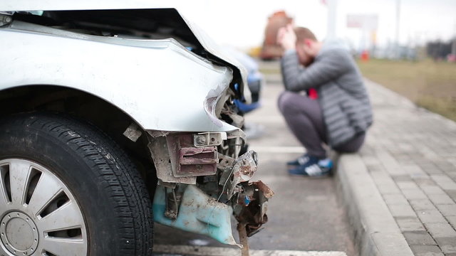  Man looking at broken car after accident