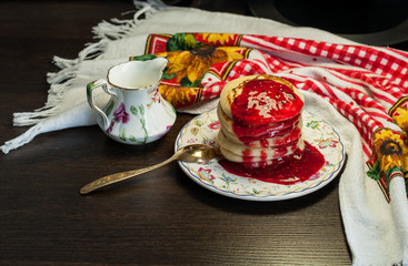 bright, tasty dessert and pancakes with jam on a table, against a dark background, in  cafe.