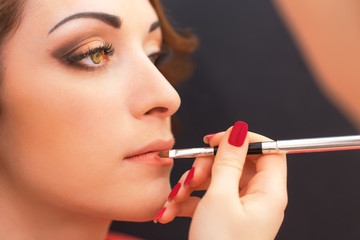 Applying lip products on a woman face.