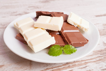 Porous white chocolate and milk chocolate on a white wooden back