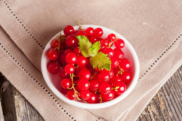 bowl of red currant on wooden background, horizontal close-up