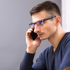 Young business man in glasses speaking on phone