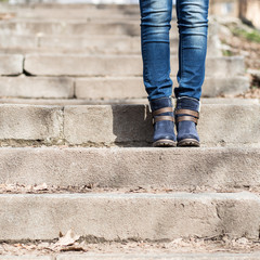Fototapeta na wymiar Female legs in winter boots and jeans on stairs
