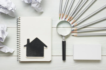 Real estate concept - magnifying glass, pencils and blank business card on wooden table. Copy space for text