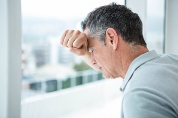 Tensed man leaning on glass window 