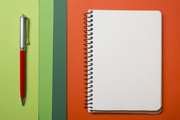 Office desk table with supplies top view. Notepad, pen and colorful paper. Copy space for text