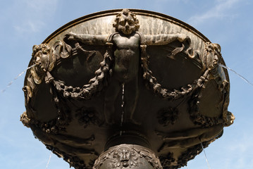 Historical bronze round fountain detail, with sprinkling water, with statue and face