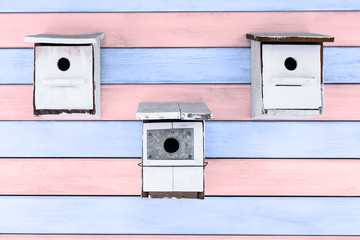 tres cajas nido blancas sobre fondo de madera rosa y azul