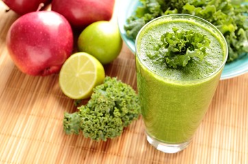 Glass with healthy smoothie with green kale, apple and lime