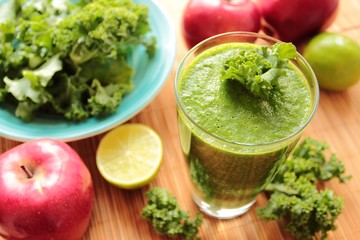 Very healthy smoothie with green kale leafs, red apples and lime in a glass