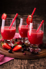Glasses of fresh cold smoothie with fruit and berries, on wooden background, healthy detox drink