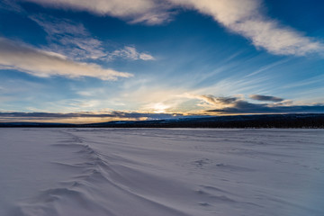 Fototapeta premium Winter landscape with forest, cloudy sky, road and snow and ice road 