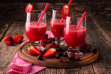 Glasses of fresh cold smoothie with fruit and berries, on wooden background, healthy detox drink
