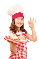 happy little girl cook with sweet donuts and ok hand sign