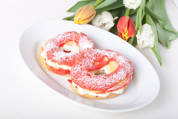 Homemade custard cakes with cream and bunch of spring tulips on