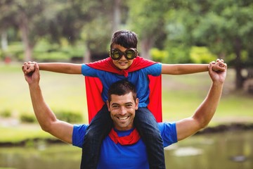 Boy in superhero costume sitting on fathers shoulder