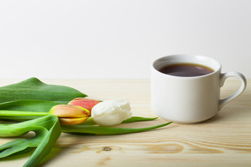 Cup of tea and bunch of spring tulips on the table. Toned
