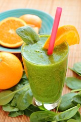 Glass with healthy smoothie with spinach and orange