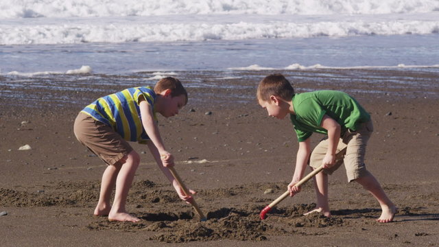 Two boys playing in sand at beach