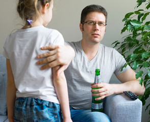 Little girl disturbing her dad while he is watching TV.