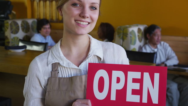 Portrait of restaurant owner with open sign
