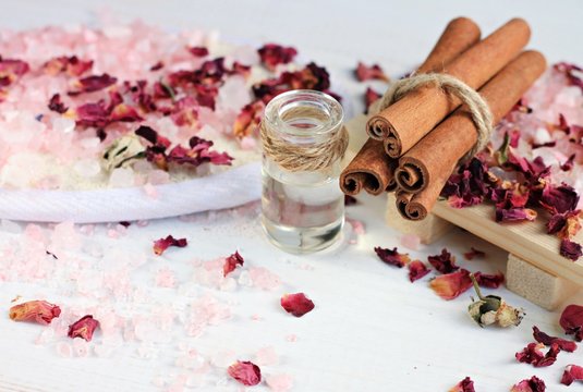 Aroma Spa Treatment. Pink Epsom Bath Salt, Essential Cinnamon Oil In Bottle, Rose Petals Scattered. 