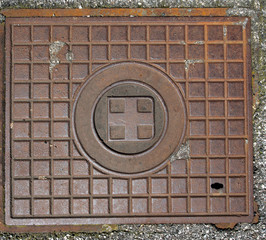 Rusty Manhole Cover / Metal brown rusty manhole cover on a pedestrian walkway