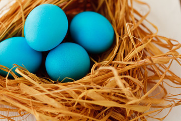 Multicolored Easter eggs in wicker basket on white wooden background
