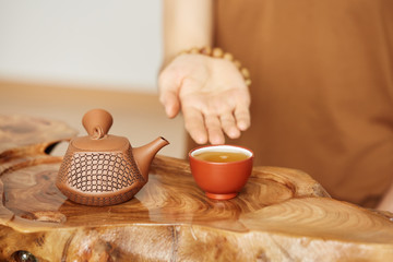 Young man sitting in meditation pose in front of tea set. Relaxation concept