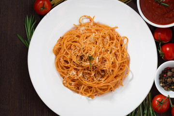 Spaghetti with tomato sauce and ingredients on a wooden table