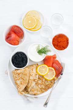 traditional Russian crepes with caviar and salted fish, top view