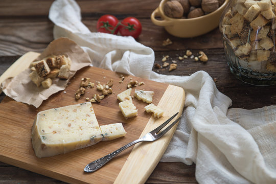 Close up of cheese with croutons and walnuts on cutting board