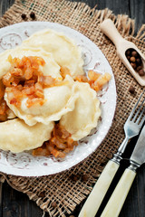 traditional Ukrainian and Russian cuisine , dumplings called varenyky of dough with meat, pepper and fat or salo in a clay plate on a dark wooden background
