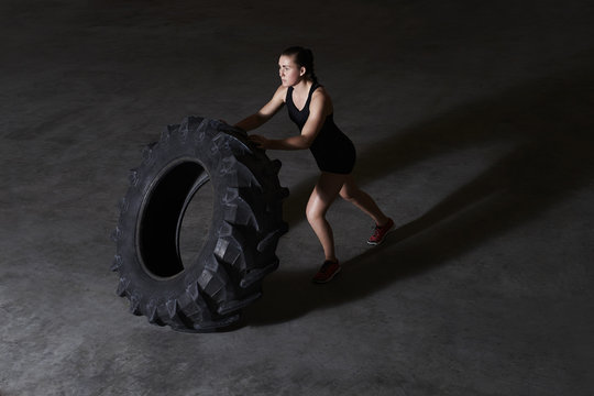 Athlete woman lifting tire in gym